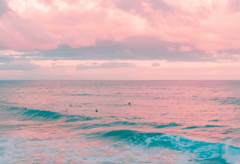 Calm ocean at sunset with a pink sky and teal water